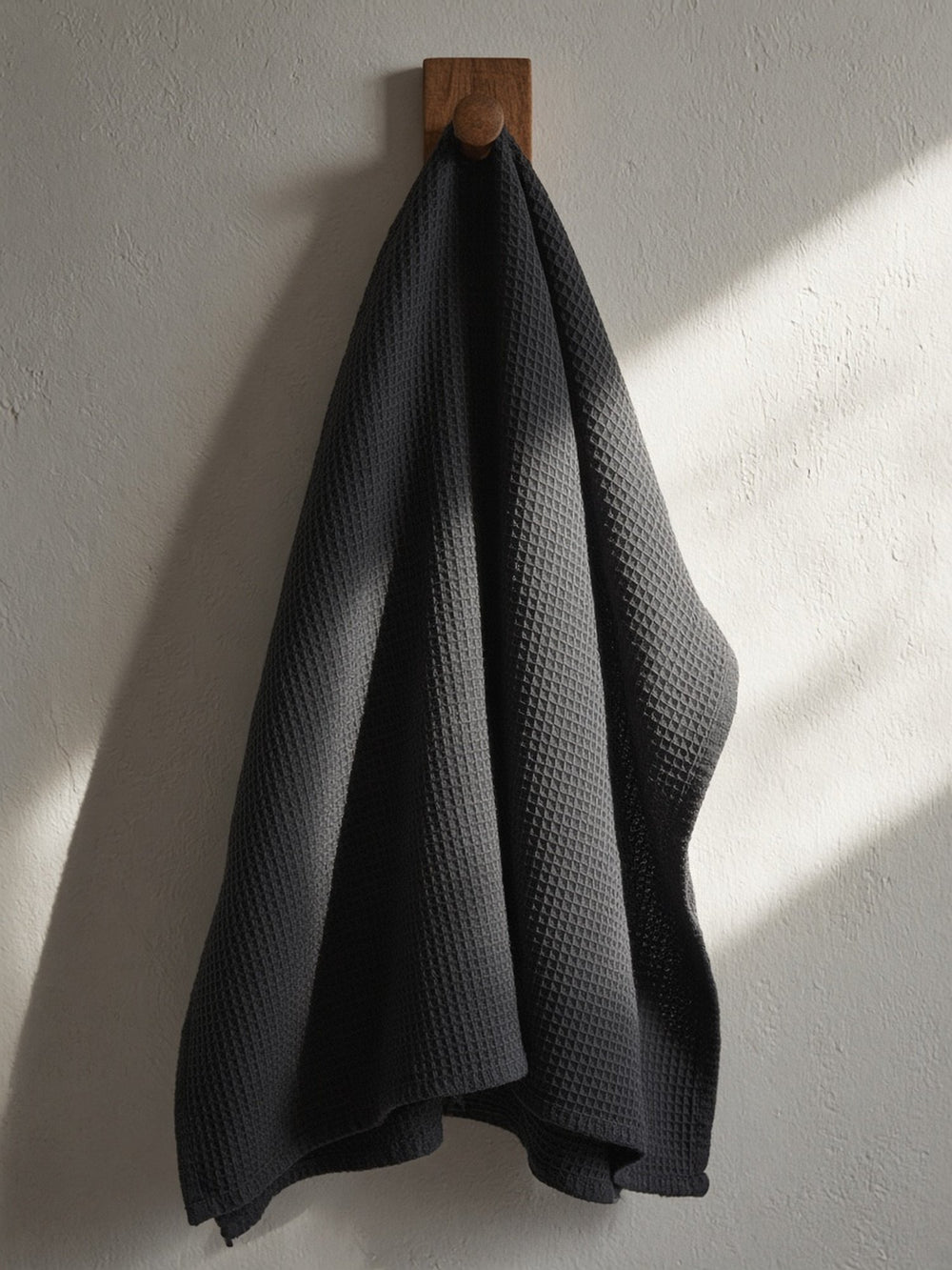 Sumi Black towel drying on a wooden hook